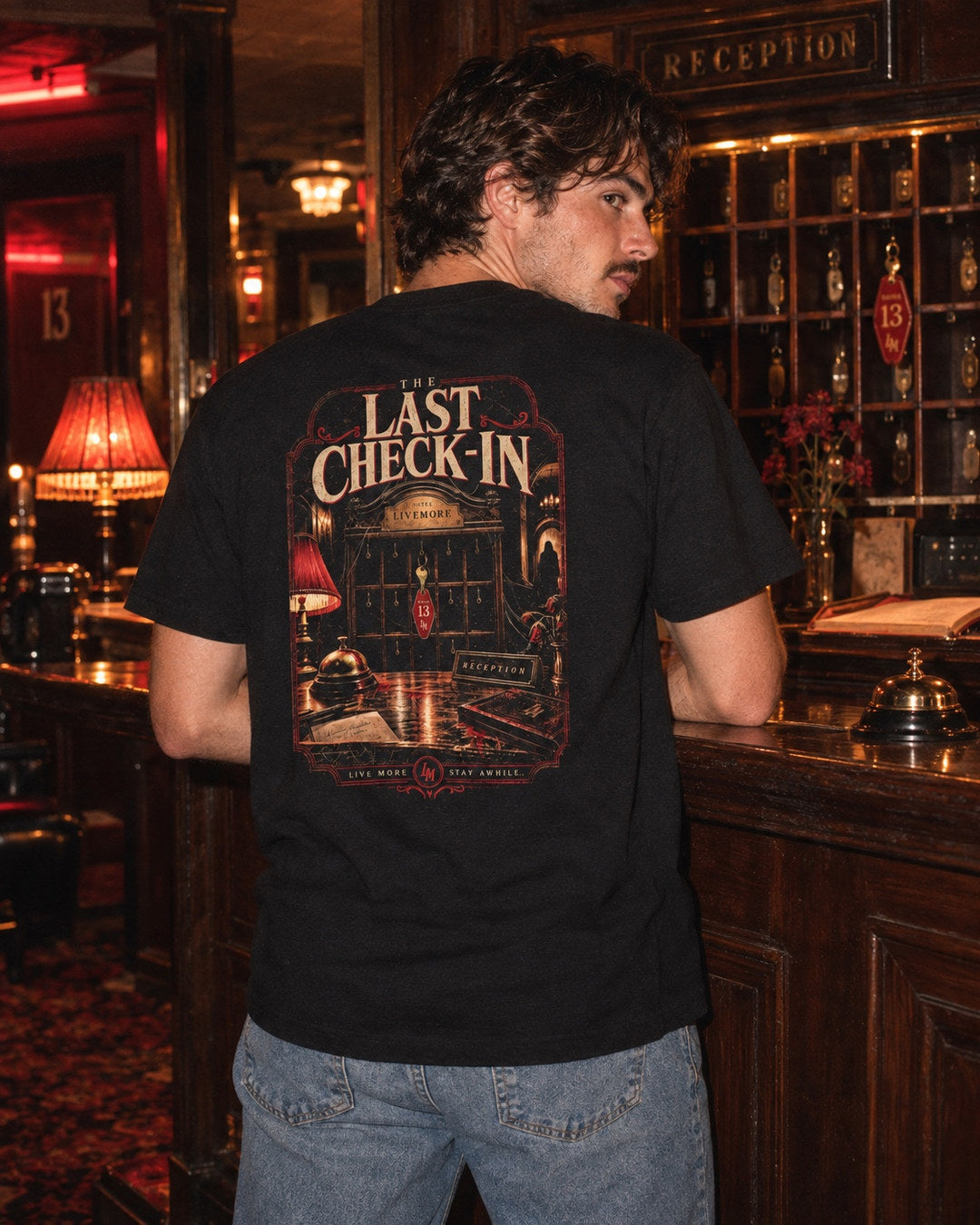 Man wearing The Last Check In shirt inside a spooky vintage motel lobby